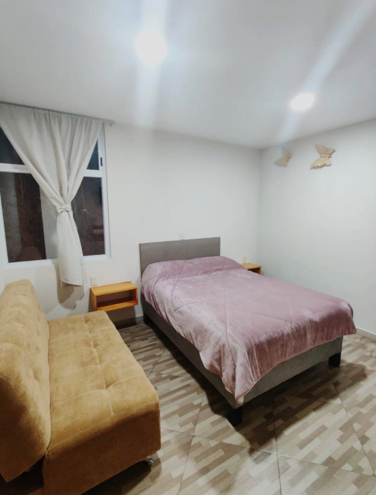 Habitación Matrimonial con cama vestida y sillón lateral.